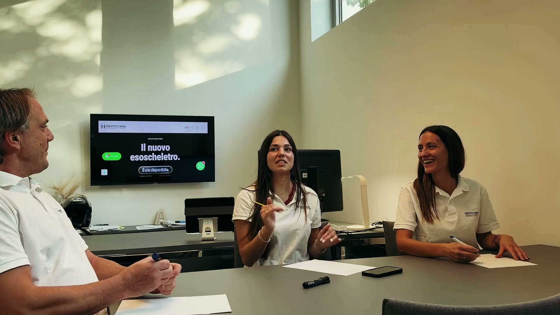 Tre persone del team NEXTTOSKIN in riunione attorno a un tavolo, nella sede di Modena